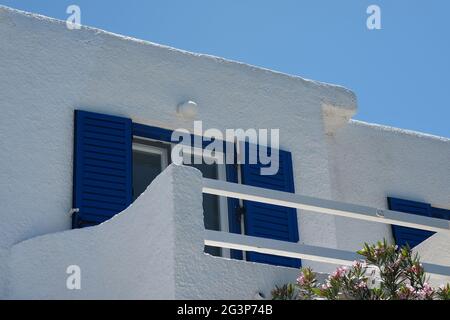 A white washed house with blue window shutters and a balcony in Ios Greece Stock Photo