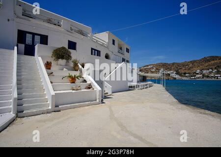 Ios, Greece - May 16, 2021 : A  whitewashed hotel that rents rooms, with the typical Cycladic architecture,  in front of the famous Mylopotas beach in Stock Photo