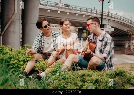 The Guy Is Playing On The Guitar To His Friends Outdoor. Stock Photo