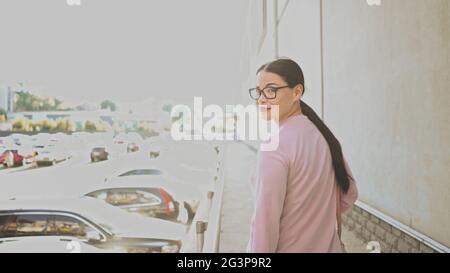 An Asian brunet businesswoman in glasses looks around and walking outside on sunny day Stock Photo