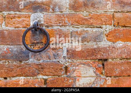 A rusty metal ring embedded in a red brick wall. Copy space for text Stock Photo