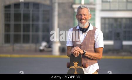 Light-skinned attractive bearded man having fun holding a longboard Stock Photo
