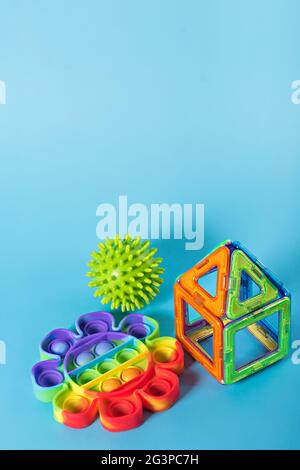 Rainbow Pop it and children's magnetic designer for development of motor skills, thinking and imagination. construction assembled on pink fidget toy o Stock Photo