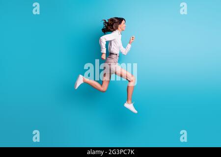 Full size profile photo of brunette girl jump run wear shirt skirt sneakers isolated on teal background