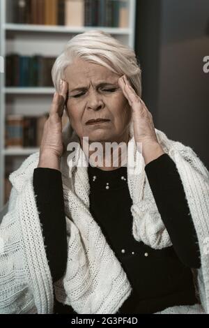 Expressive Elderly Blonde Feels A Headache From Stress Stock Photo