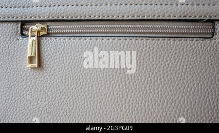 Natural or artificial leather texture. Fragment of a beige or powdery bag with a zipper and stitching. Zipper or clasp bag design element. Bovine skin Stock Photo
