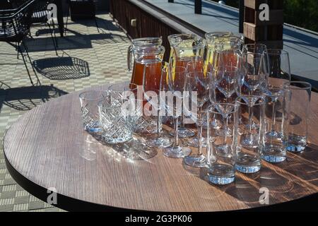 A set of empty glasses displayed in rows and a decanters of cool lemonade or juice for the party or wedding. Summer refreshing fruit-drink from apples Stock Photo