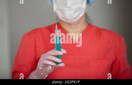 Female doctor in gloves and mask, holds a syringe for injection. Stock Photo