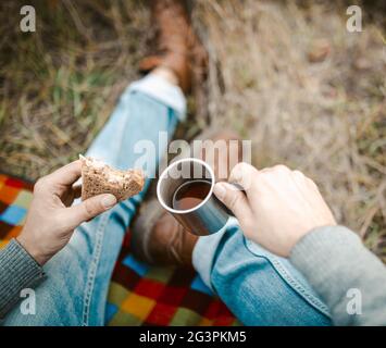 Male Traveler Eats Snack And Drinks Tea On Grass Stock Photo