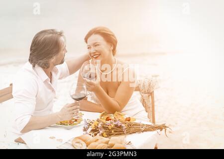 Mid aged couple with red wine sit in restaurant in beautiful style. Happy elderly concept Stock Photo