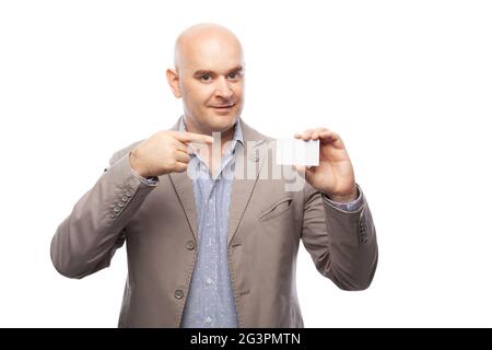 A bald man in a beige suit shows a business card isolated on white. Stock Photo