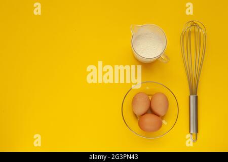 Whisk and a plastic cup for whipping on a yellow background. Stock Photo