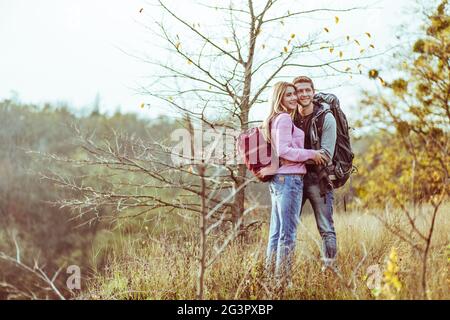 Hugs on top of the hill. Couple of lovers tourists cuddling while looking at the camera. Copy space at left side Stock Photo