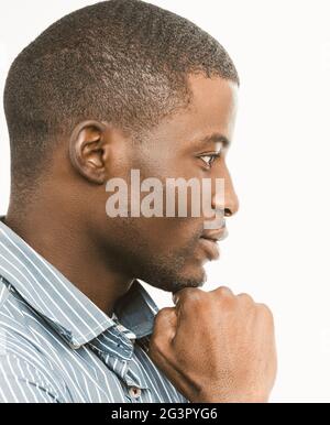Thoughtful African American man touches his chin looking to the side. Profile view of short-haired handsome guy on white backgro Stock Photo
