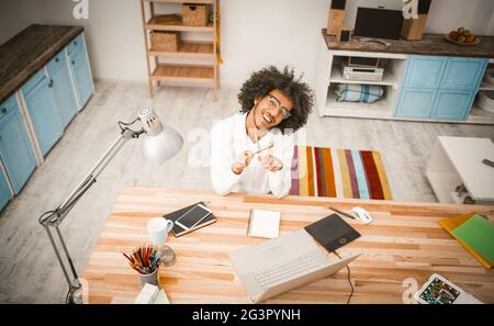 Jolly young businessman took break from work. Cheerful arab guy play with pencils looking at camera while sitting at workplace i Stock Photo