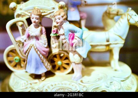 Antique porcelain figurine of couple courting outside horse drawn carriage. Collectables in Antique Store in Chester, New Jersey, USA Stock Photo