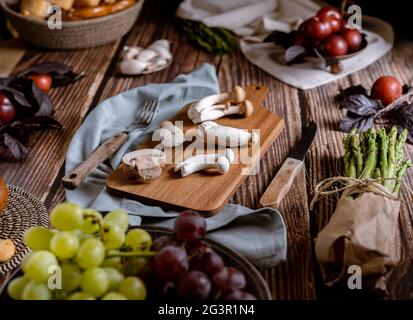 Dark photography of mushrooms, asparagus, bread, garlic and plums on a table of old wood. Vegetables recipe of for autumn or winter. Moody picture of Stock Photo