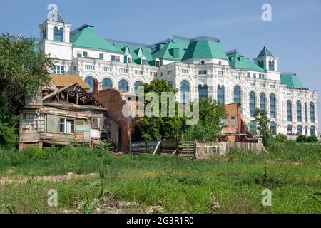 Astrakhan/Russia-20.06.2016:The contrast of russian reality: old abandoned house and new and modern theatre in Astrakhan Stock Photo