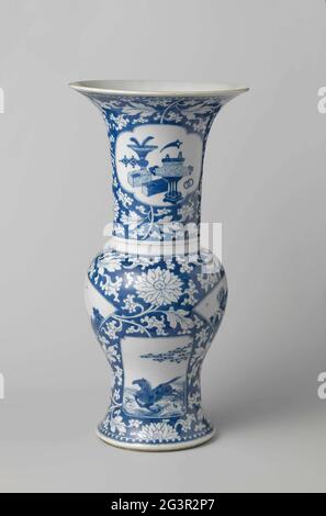 Baluster Beaker Vase With Flower Scrolls And Panels in Reserve. Baluster-shaped cup spring from porcelain with trumpet-shaped mouth, painted in underglaze blue. The belly and neck are covered with underglaze blue with flower drinks in reserve; Two fan-shaped cartouches with two people in a landscape and flower branches with a bird, spent two sprawn rectangular cartouches with a flying horse above waves and two deer under a tree in which a crane is sitting. On-neck two saved, lobed cartouches with floral basket and the other with antiques (vase with peacock feathers, whose burner, books) and va Stock Photo