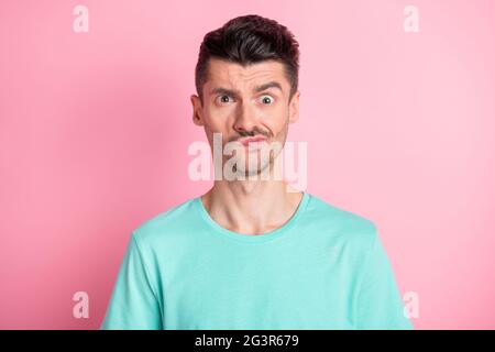 Portrait of young unhappy annoyed displeased stressed man in teal t-shirt look camera isolated on pink color background Stock Photo