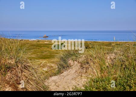 Image of St Ouens Bay from the sand dunes with Rocco Tower and blue sky. Selective Focus Stock Photo