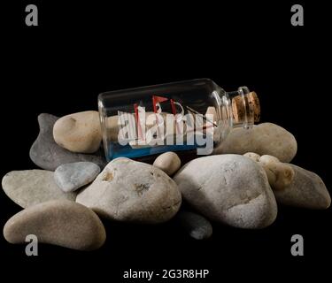 Small sea stones in a glass vessel. The idea of decorating the house with small  rocks in a jar on a wooden blurred background. Stock Photo