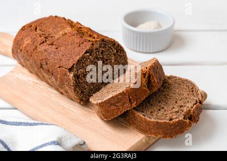Freshly baked rye bread sliced on wooden board. Light wooden background with copy space Stock Photo