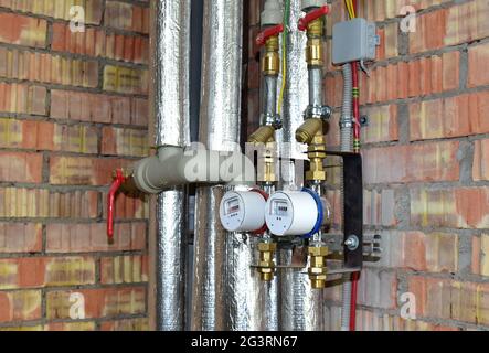 Water meter of cold and hot water on the brick wall background in new flat. Devices for measuring the amount of consumed water Stock Photo
