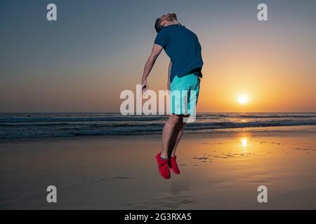 Man jumping on nature, silhouette in the sunset. Amazing view on sunset beach. Stock Photo