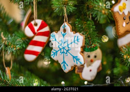 Christmas tree branch with wooden decorative toys and gingerbread homemade sweet cookie on dark background, selective focus. New Stock Photo