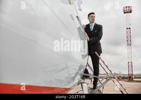 Flight attendant standing on ladder of airplane Stock Photo
