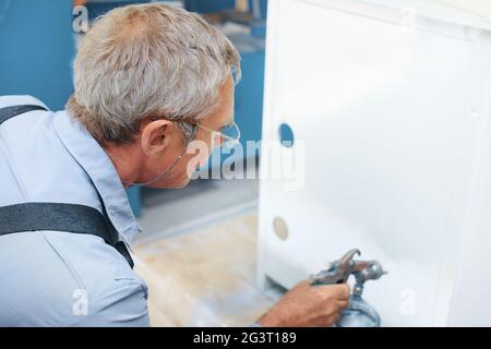 Metal spray gun for painting in a paint shop. Accessories for painting  works and protective clothing. Dark background Stock Photo - Alamy