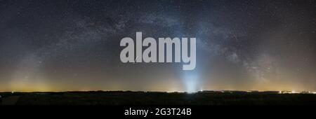 Panorama of Milky Way bow over rural landscape with lights of Spangdahlem Air Base in distance, Germany Stock Photo