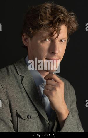 Pensive man looks at camera touching his chin with hand. Close up portrait. Isolated on black background Stock Photo