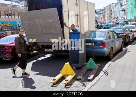 Men load an ATM into van on city street. Stock Photo