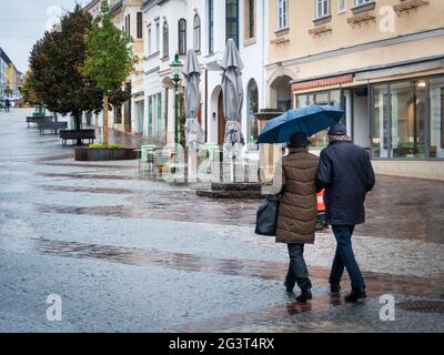 Couple elderly people walking in the rain in the city Stock Photo
