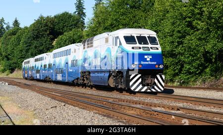 Mukilteo, WA, USA - June 16, 2021; Northbound blue and white Sounder commuter train passes Mukilteo with evening service from Seattle to Everett Stock Photo