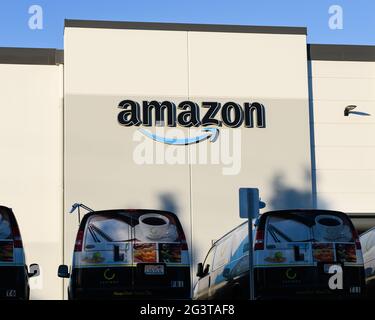 Everett, WA, USA - June 16, 2021; Amazon corporate sign on a warehouse building in North Everett, Washington State with company delivery vans Stock Photo