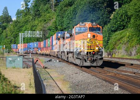 Mukilteo, WA, USA - June 16, 2021; Southbound BNSF freight train approaches Mukilteo with a shipment of colorful stacked containers Stock Photo