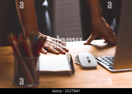 Close-up of women's hands with equipment on the employee's desk, the project manager checks or helps the specialist to bring out Stock Photo