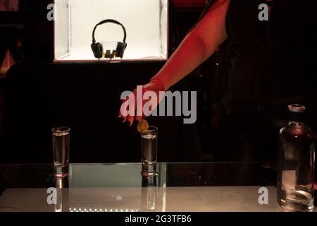 Pair of tequila glasses containing alcoholic beverage distillate burning agave water on the bar counter,  decorated with a lemon wedge at background a Stock Photo
