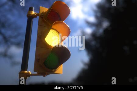 Outdoor vertical traffic light with blue sky and trees around. Traffic control concept image with shallow depth of field. Stock Photo