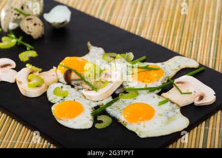 Fried quail eggs with champignons Stock Photo