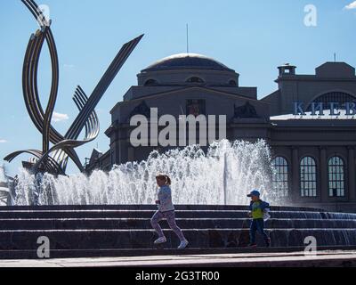 Children play against the background of the fountain and the sculpture "The Abduction of Europe" by the Belgian sculptor Olivier Strebelle. The sculpture is installed on Europe Square near the Kiev railway Station. Stock Photo