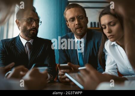 Young team of colleagues app developers testing the bugs of the new app while testing usability with different operation system Stock Photo