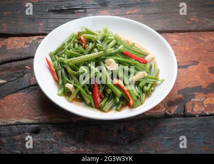 Thai food stir fried morning glory on rustic wooden table Stock Photo