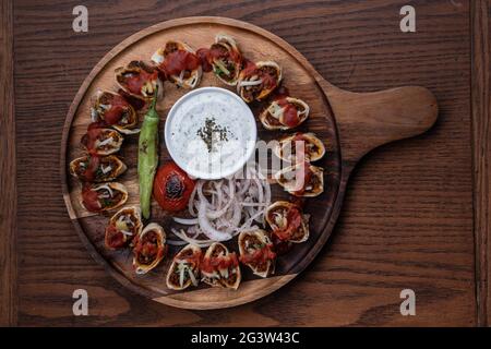 Turkish Beyti kebab served with grilled vegetables and yoghurt sauce on wooden table Stock Photo