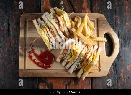 Chicken club sandwiches and french fries on rustic wooden table Stock Photo