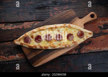 Turkish pide with sausage on rustic wooden table