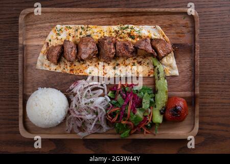 Turkish lamb sis kebab with rice and vegetables on wooden table Stock Photo